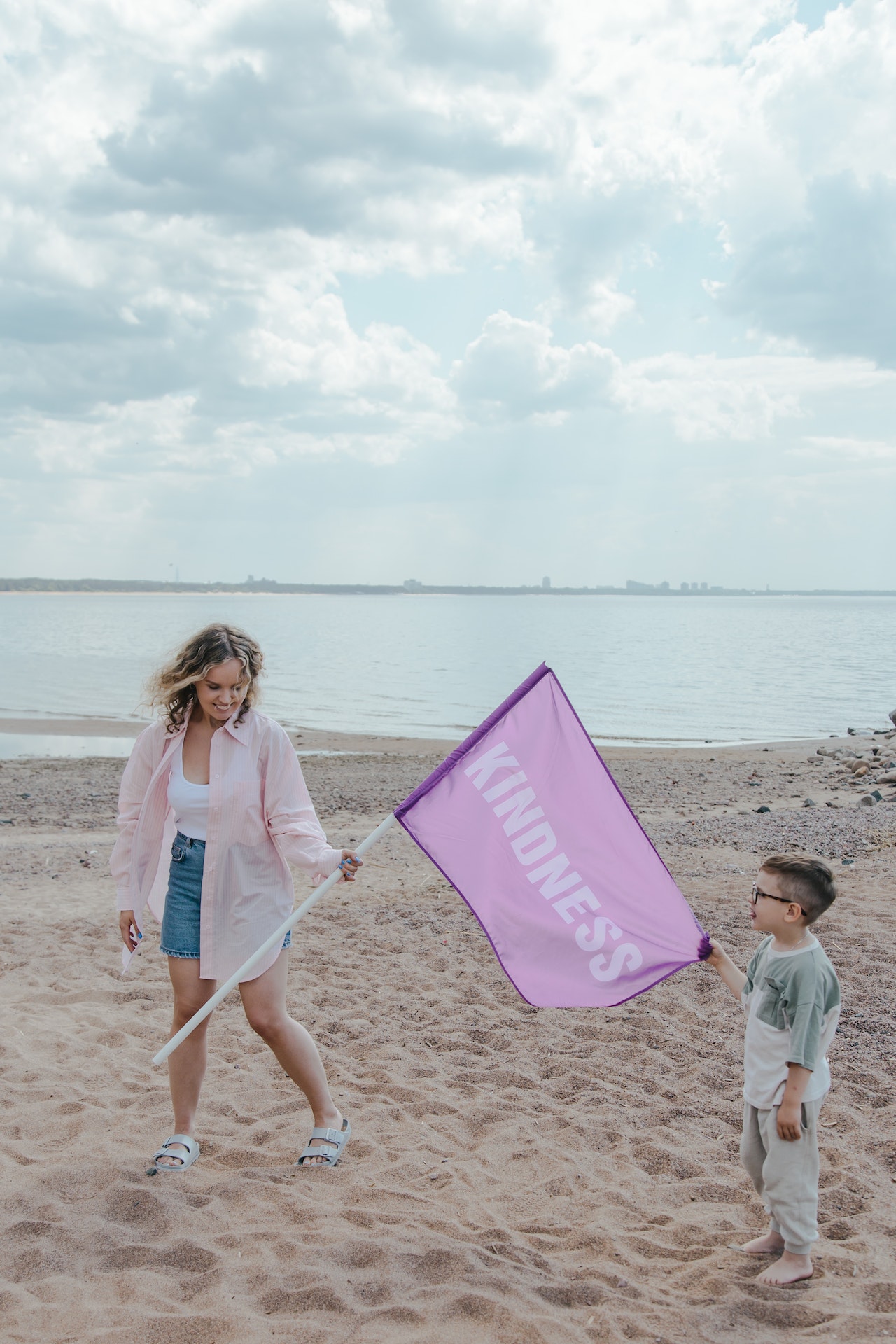 Woman in pink sleeves handing over 'kindness flag' to a kid.