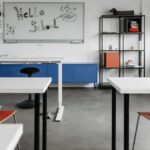 Empty chairs and desks of a classroom; and a white board for writing.