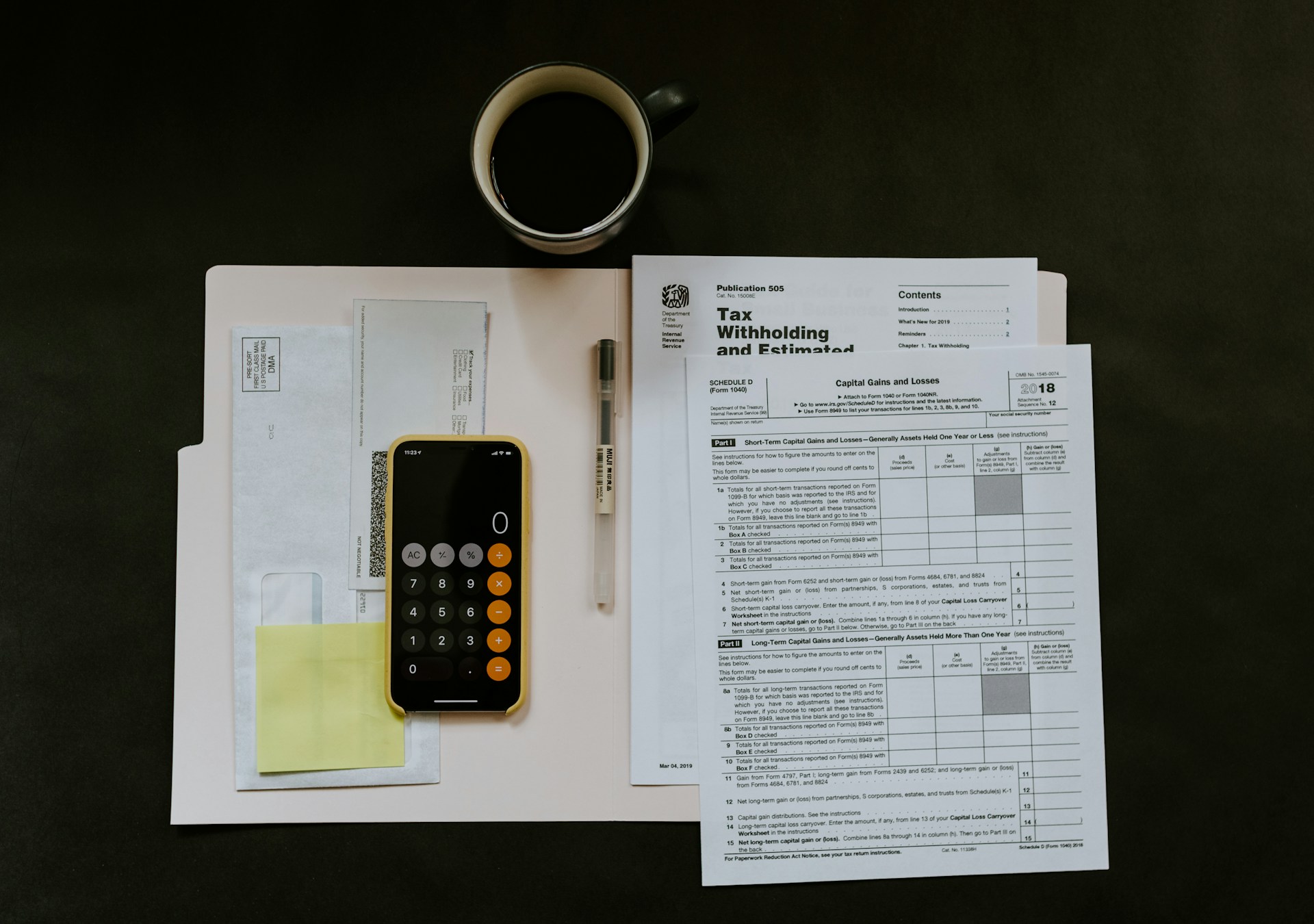 Bills, expenses, and tax related papers along with a coffee mug on a table.