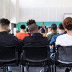 A classroom with students from diverse ethnic backgrounds sitting on chairs.