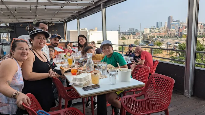 Kids and elders posing to camera while eating on a table at Avanti F&B, Denver.