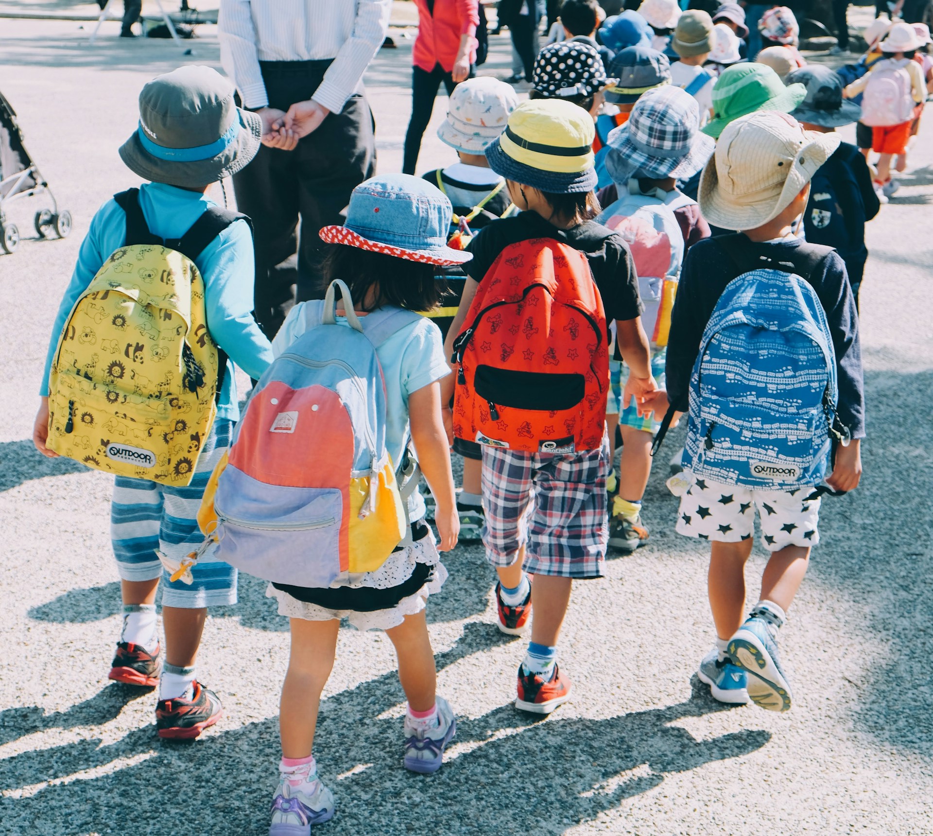 A group of school children attending school with school bags hung at their backs.