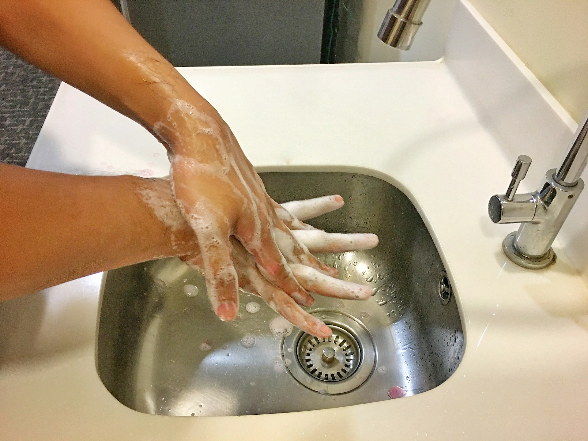 Washing hands with soap in a sink.
